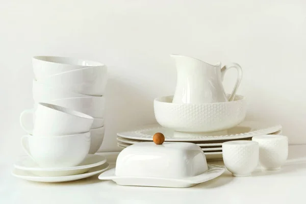 Bílé nádobí k servírování. Příbory, misky, nádobí a další různé bílé věci na bílý stůl top. Kuchyňské zátiší jako pozadí. Kopírovat prostor. — Stock fotografie
