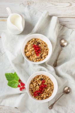 Granola iki kişi için yaz sağlıklı kahvaltı, müsli süt ile sürahi ile kırmızı kuş üzümü dekor ahşap tahta üzerinde. Üstten Görünüm.