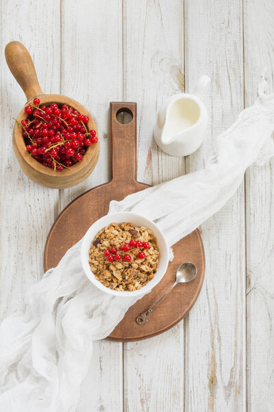 Summer healthy breakfast for two person of granola, muesli with milk jug with red currant decor on wooden board. Top view.