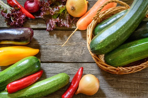 Calabacín en canasta de mimbre con verduras alrededor en mesa de madera. Cosecha. Vista superior . —  Fotos de Stock