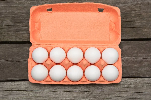 Karton van biologische eieren op een houten bord. Bovenaanzicht. — Stockfoto