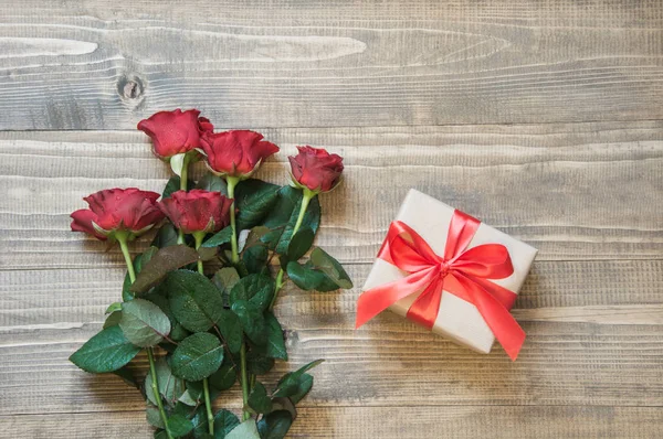 Букет красных роз с подарком на деревянной доске. Вид сверху . — стоковое фото