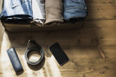 Açık bavul erkek giyimi, mobil, kemer ahşap zemin üzerinde seyahat için. Yukarıdan görüntülemek.