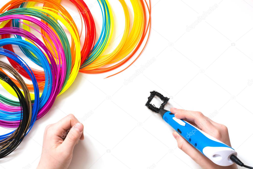 Child draws 3Dpen. Colorful rainbow plastic filaments for 3D pen laying on white. New toy for child.
