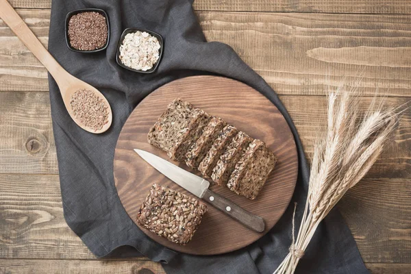 Una hogaza de pan de centeno entero rústico fresco con ingredientes en un tazón sobre tabla de madera, fondo rural. Vista superior. Copiar espacio . —  Fotos de Stock