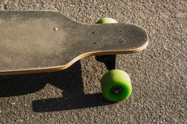 Eski longboard yerde kullanılır. Siyah kaykay bir boş asfalt yol üzerinde. Yakın çekim.