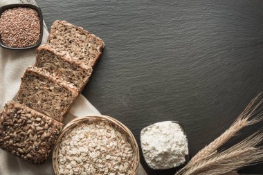 Fitness kepekli çavdar ekmeği. Tohumlar üzerinde siyah arduvaz çanak ile dilimlenmiş çavdar ekmeği somun. Üstten Görünüm.