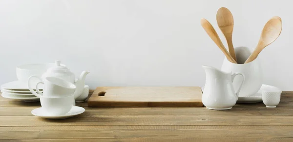 Utensílios de cozinha brancos, louça e outras coisas brancas diferentes para servir na placa de madeira branca . — Fotografia de Stock