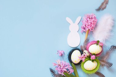 Paskalya kavramı. Beyaz tavşan ve mavi çiçek dekorasyonu ile boyalı tavuk yumurtası. Üstten Görünüm. Düz yatıyordu.