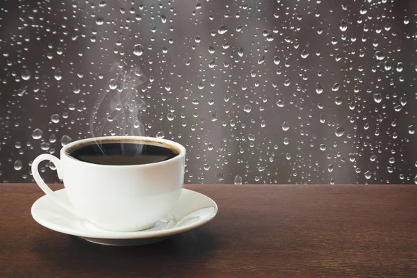 Tasse chaude de café noir dans une journée pluvieuse sur la table . — Photo