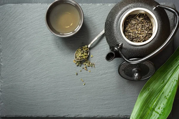 Té verde japonés en pizarra negra. Tetera negra con té verde seco. Preparación del té. Vista superior con espacio de copia . —  Fotos de Stock