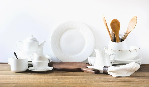 Utensílios de cozinha brancos, louça e outras coisas brancas diferentes para servir na placa de madeira branca . — Fotografia de Stock