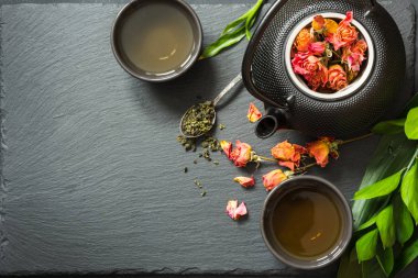 Yeşil çay siyah arduvaz arka plan üzerine kuru gül çiçek ile. Üstten Görünüm, kopya alanı.