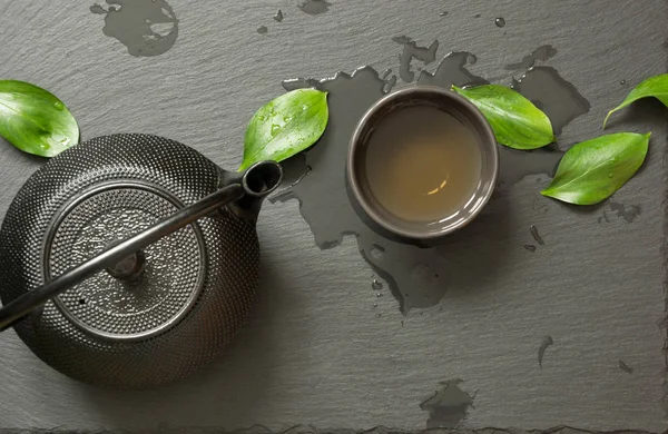 Japán zöld tea fekete pala háttér. Fekete teáskanna és a zöld tea ivás. Felülnézet, másol hely. — Stock Fotó