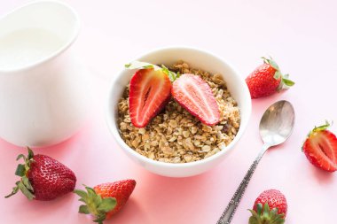 Sağlıklı kahvaltı granola, çilek ve süt pembe üzerinde. Yaz.