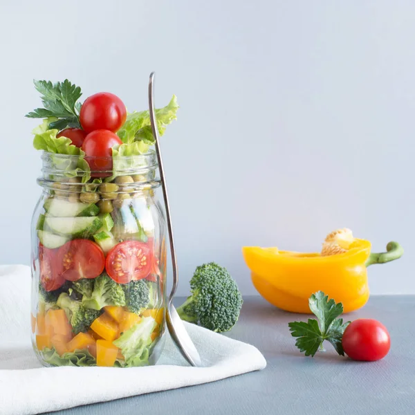 Zdravé domácí Barevný salát v mason jar s rajčaty, salátem, žluté pepřovou na modré. Kopírovat prostoru. Oběd pro práci. Sada potravin. — Stock fotografie