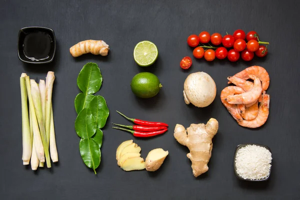 Ingredientes para la popular sopa tailandesa Tom-yum kung. Lima, galangal, chile rojo, tomate cherry, limoncillo y hoja de lima kaffir sobre tabla negra. Acostado. Vista superior . —  Fotos de Stock