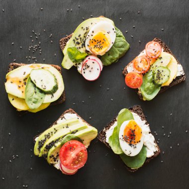 Farklı sandviç sebze, yumurta, avokado, domates, Siyah Kara tahta üzerinde çavdar ekmeği. En iyi vew. Meze parti için. Düz yatıyordu.