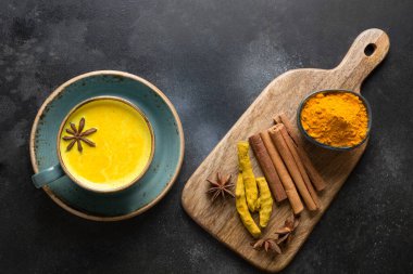 Bir fincan ayurvedic altın zerdeçal sütlü ve siyah üzerine anason tozu ve anason yıldızı. Yukarıdan görüntüle.