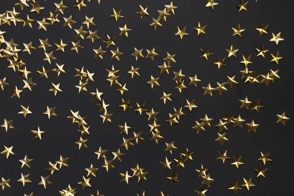 Goldene Sterne glitzern auf schwarzem Hintergrund. Festliche Feiertagskulisse. — Stockfoto