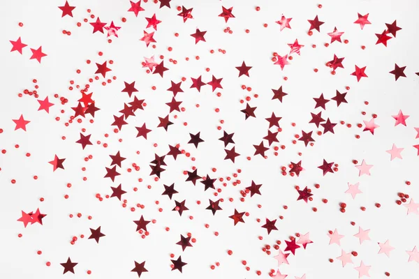 Fête en toile de fond de vacances avec des étoiles rouges confettis paillettes sur fond blanc. Style à plat. À Noël. Bonne année . — Photo