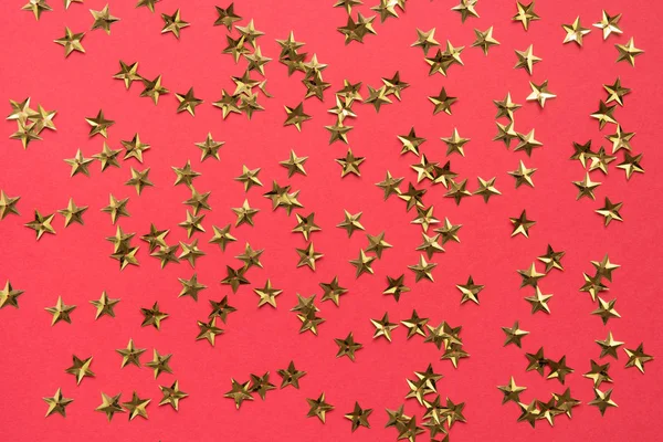 Goldene Sterne glitzern Konfetti auf rotem Hintergrund. Festliche Feiertagskulisse. — Stockfoto