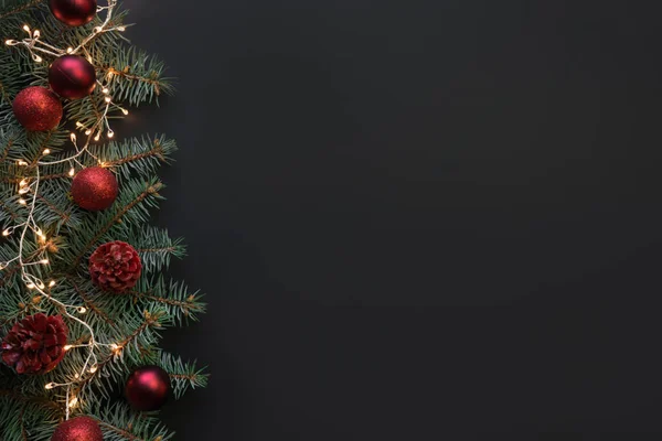 Weihnachtsrahmen mit Tannenzweigen, roten Kugeln, Girlanden auf schwarzem Hintergrund. Platz für Text, Blick von oben, flache Lage. — Stockfoto