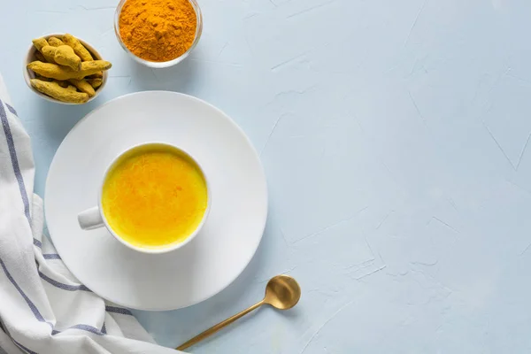 Cup of ayurvedic golden turmeric milk with honey on blue. Space for text or recipe. Healthy drink for immunity. Top view. Natural food — Stock Photo, Image