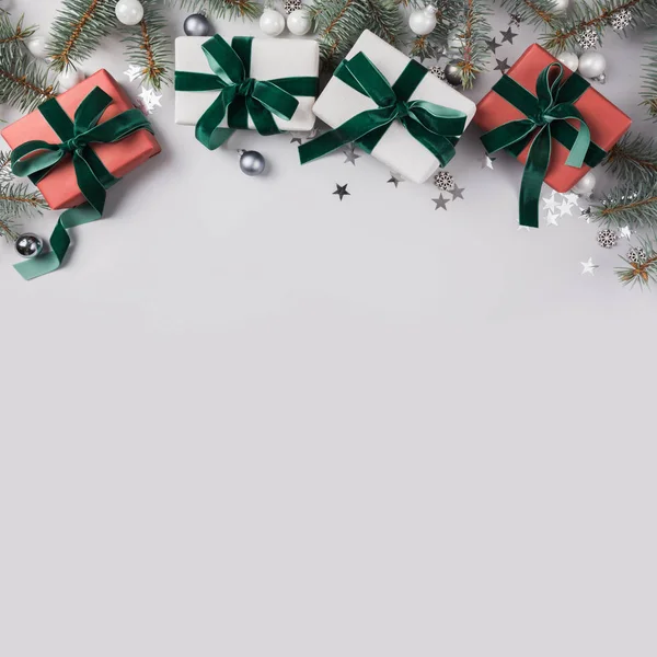 Composición navideña con regalos rojos, árbol de ramas de abeto sobre fondo gris. Tarjeta de Navidad. Vacaciones de invierno. Feliz Año Nuevo . — Foto de Stock