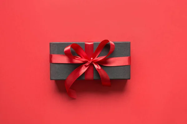 붉은 리본으로 싸인 검은 선물 상자붉은 표면. — 스톡 사진