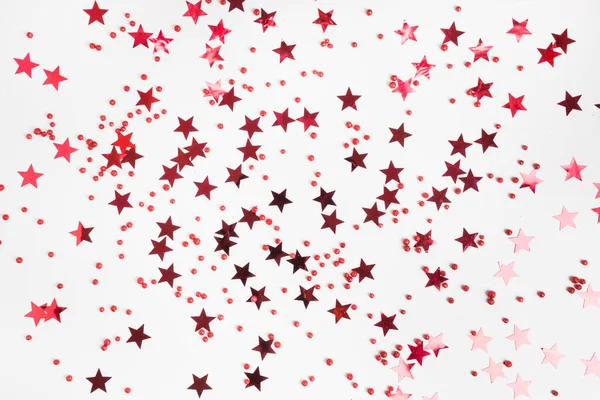 Party-Urlaubskulisse mit roten Sternen glitzert Konfetti auf weißem Hintergrund. flacher Lagestil. Weihnachten. frohes neues Jahr. — Stockfoto