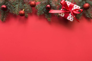 Noel çerçevesinde köknar dalları, kırmızı toplar, kırmızı arka planda çelenkler. Metin için boşluk, yukarıdan görünüm, düz yatış.