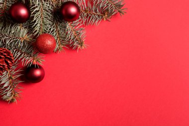 Noel çerçevesinde köknar dalları, kırmızı arka planda kırmızı toplar. Metin için boşluk, yukarıdan görünüm, düz yatış. Mutlu yıllar..