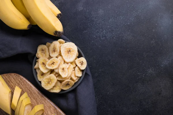 Chips de plátano deshidratados y secos sobre fondo negro. Vista desde arriba . — Foto de Stock