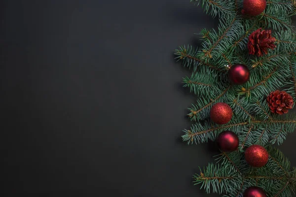 Weihnachtsrahmen mit immergrünen Zweigen, rote Kugeln auf schwarzen. Raum für Text. — Stockfoto