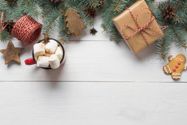 Noel ağacı dalları, ahşap oyuncaklar ve ortasında lokum olan bir fincan kahve beyaz ahşap tahtada. Üst görünüm.