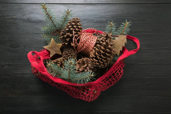 Natale zero vacanze di rifiuti. Rami di abete di conifere in eco sacchetto di cotone rosso su tavola nera. Eco friendly Natale . — Foto Stock