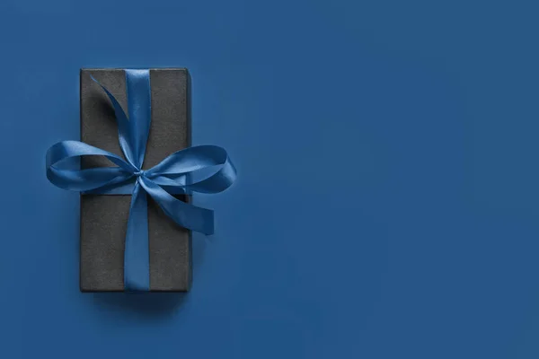 고전적 인 푸른 표면에 파란 리본으로 싸인 검은 선물 상자. — 스톡 사진