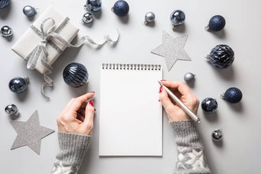 Kadın yeni yıl için hedefler, listeler, planlar ve hayaller yazıyor. Klasik Mavi Tatil dekorunda Noel için dilek listesi.