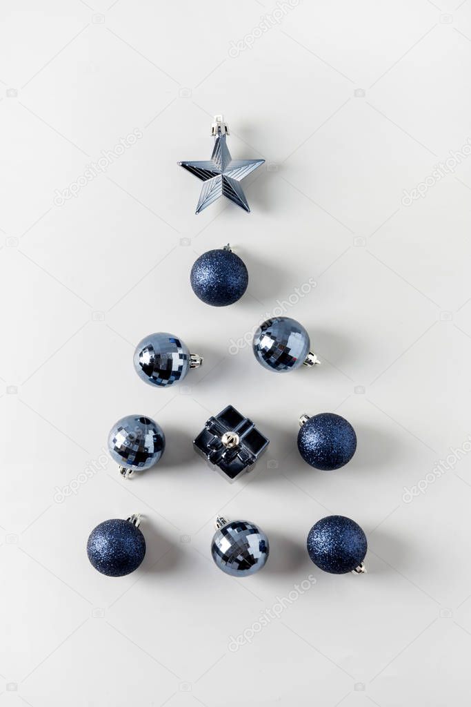 Christmas tree of classic blue balls and stars on pastel grey. Close up. Holiday greeting card. View from above.
