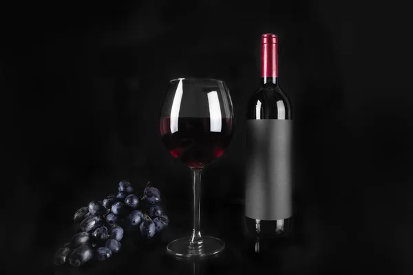 赤ワインとボトルのワイングラス、黒のブドウの束. — ストック写真