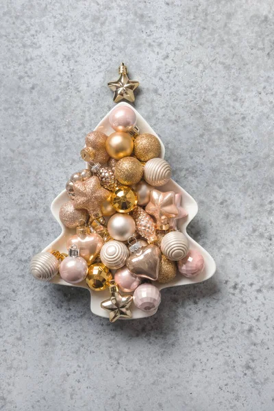 Albero di Natale decorativo di palline d'oro in piatto bianco su pietra grigia. Biglietto d'auguri natalizio. Vista dall'alto, disposizione piatta . — Foto Stock