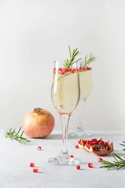 Granatäpple julcocktail med rosmarin, mousserande vin på vitt bord. Xmas Semesterdrink. — Stockfoto