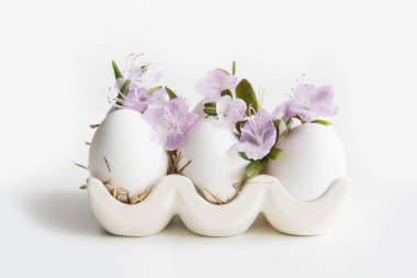 Porselen kutuda bahar çiçekleri olan organik beyaz tavuk yumurtaları. Paskalya.