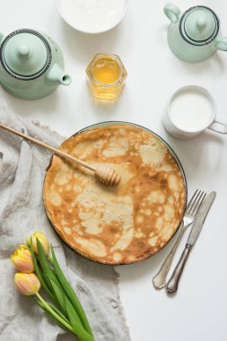 Tasty russian breakfast pancakes, milk, sour cream, honey. Springtime. Shrovetide.