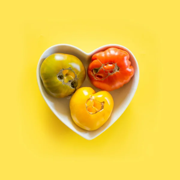 Feo tomate orgánico colorido en plato en forma de corazón. Concepto verduras ecológicas . —  Fotos de Stock