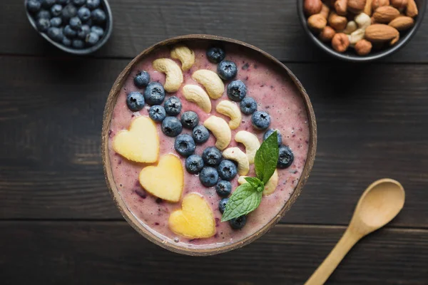 Desayuno saludable de plátano y batido de arándanos decorado con frutas en un bol de coco. — Foto de Stock