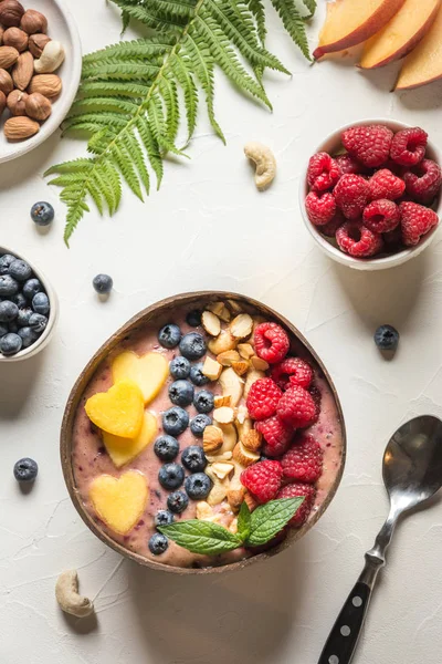 Batido de plátano y arándano sobre blanco. Desayuno saludable en un tazón de coco. Vertical — Foto de Stock