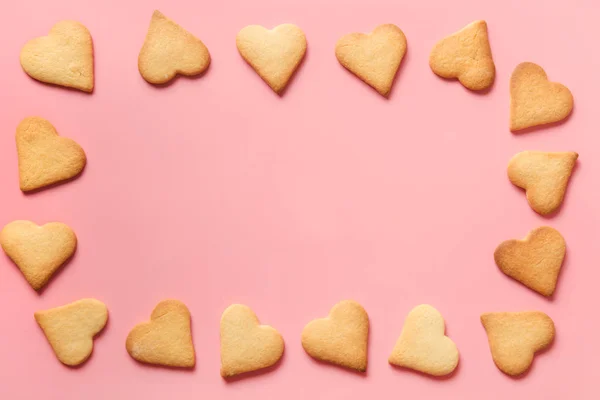 Confine di biscotti fatti in casa a forma di cuore su rosa. Posa piatta . — Foto Stock
