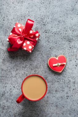 Sevgililer günü tebrik kartı, kalp kurabiyeleri, aşk mektubu, hediye, kahve fincanı gri masada. Dikey.